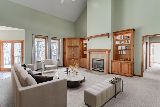 living area with high vaulted ceiling, baseboards, light colored carpet, and a tiled fireplace