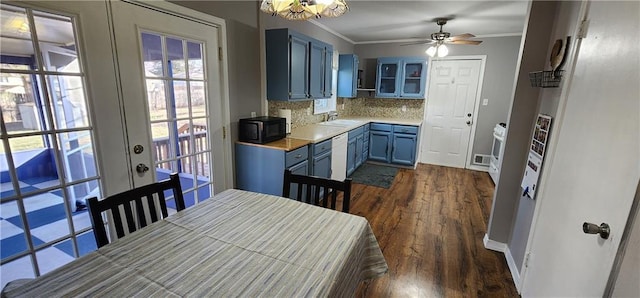 kitchen with tasteful backsplash, blue cabinetry, crown molding, black microwave, and light countertops