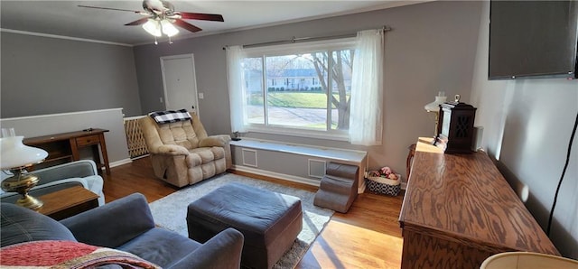 interior space featuring a ceiling fan, crown molding, wood finished floors, and baseboards