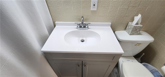 bathroom with vanity, tile walls, toilet, and a textured wall