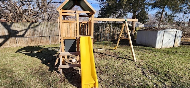 view of playground featuring a storage shed, a yard, a fenced backyard, and an outbuilding