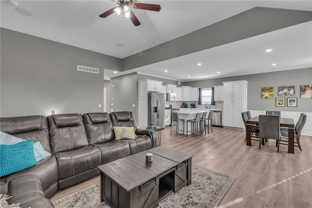 living room featuring visible vents, recessed lighting, light wood-style floors, lofted ceiling, and ceiling fan