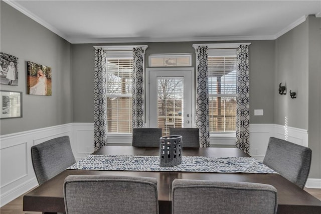 dining area featuring a wainscoted wall, wood finished floors, and ornamental molding