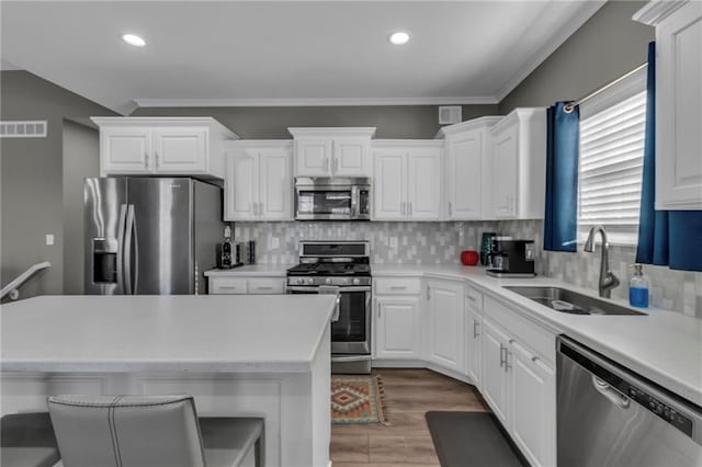 kitchen featuring visible vents, backsplash, white cabinets, stainless steel appliances, and a sink