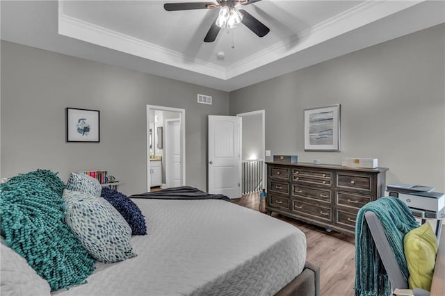 bedroom featuring visible vents, ornamental molding, a raised ceiling, and wood finished floors