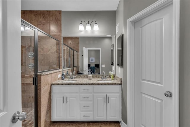 full bathroom with a shower stall, double vanity, ensuite bathroom, and a sink