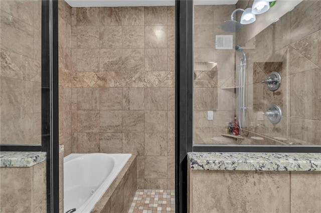 bathroom with a relaxing tiled tub, visible vents, and a tile shower