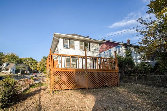 rear view of house featuring fence and a wooden deck