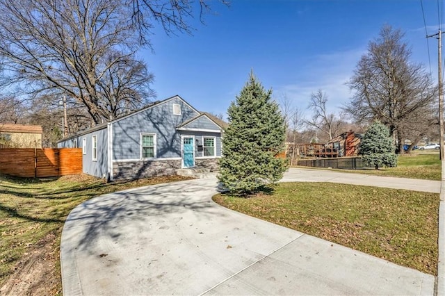 view of front of property featuring concrete driveway, fence, and a front lawn