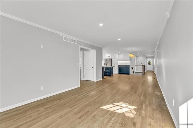 unfurnished living room with visible vents, crown molding, baseboards, recessed lighting, and light wood-style flooring