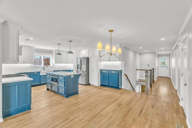 kitchen with light countertops, blue cabinetry, light wood finished floors, and appliances with stainless steel finishes