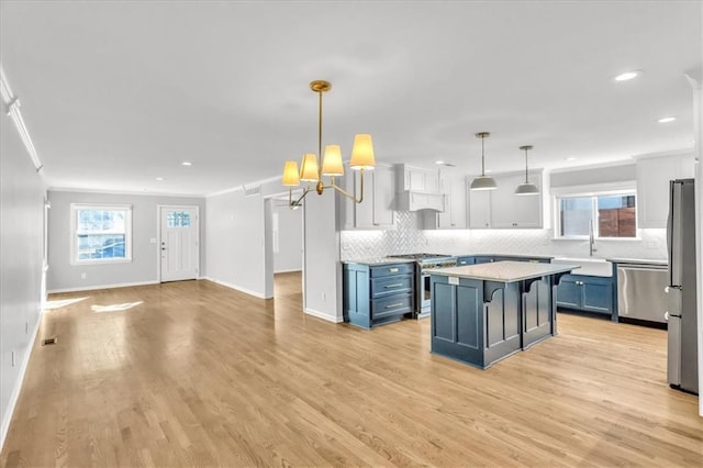 kitchen featuring blue cabinetry, stainless steel appliances, backsplash, and light countertops