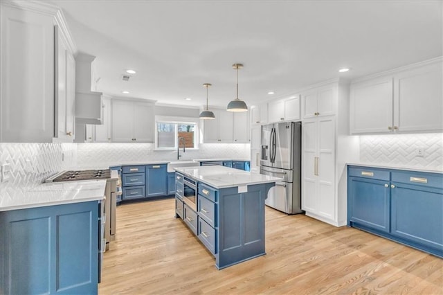 kitchen with light wood-style flooring, appliances with stainless steel finishes, blue cabinets, and a sink