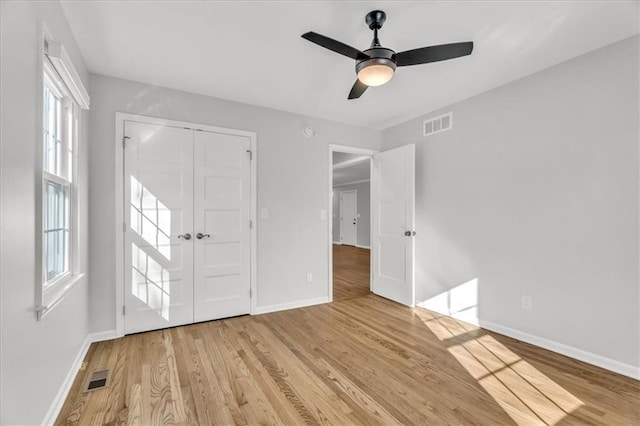 interior space with visible vents, baseboards, a ceiling fan, and wood finished floors