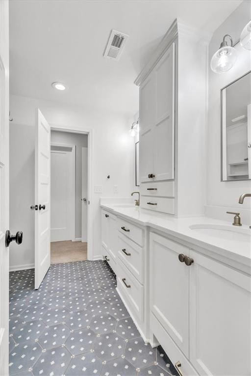 full bath featuring a sink, visible vents, baseboards, and double vanity