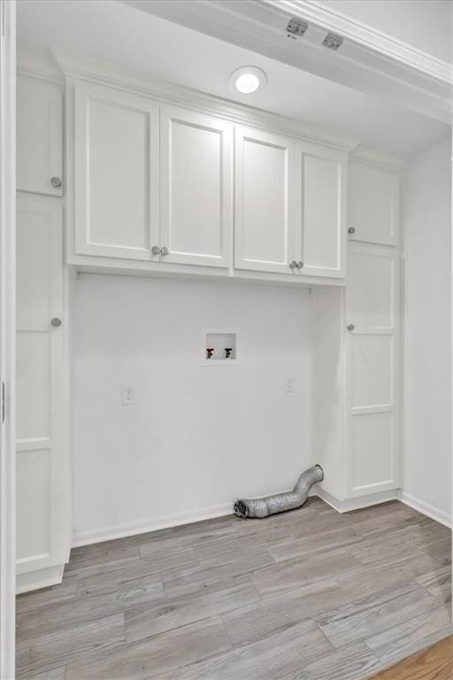 clothes washing area featuring cabinet space, light wood-style flooring, baseboards, and washer hookup