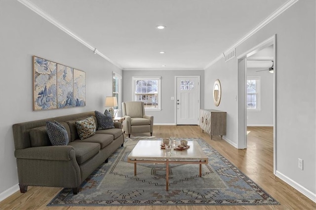 living room featuring baseboards, wood finished floors, visible vents, and ornamental molding