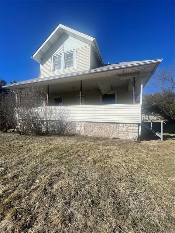 view of side of home with a lawn and covered porch