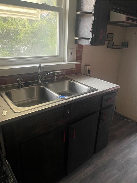 kitchen with decorative backsplash, light countertops, wood finished floors, and a sink