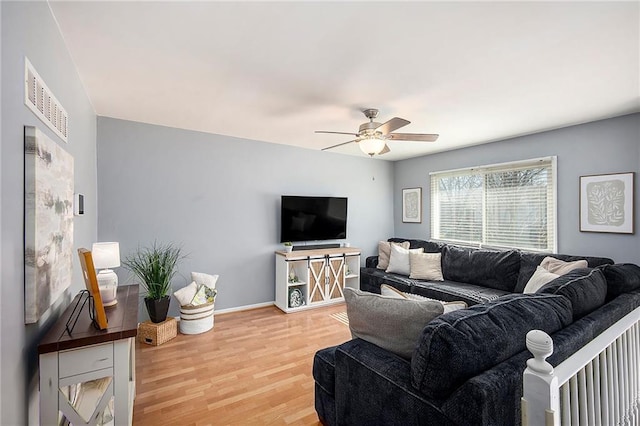 living area with light wood-type flooring, visible vents, baseboards, and a ceiling fan