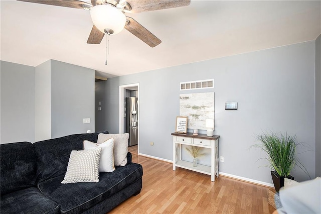 living area featuring baseboards, visible vents, light wood-type flooring, and ceiling fan