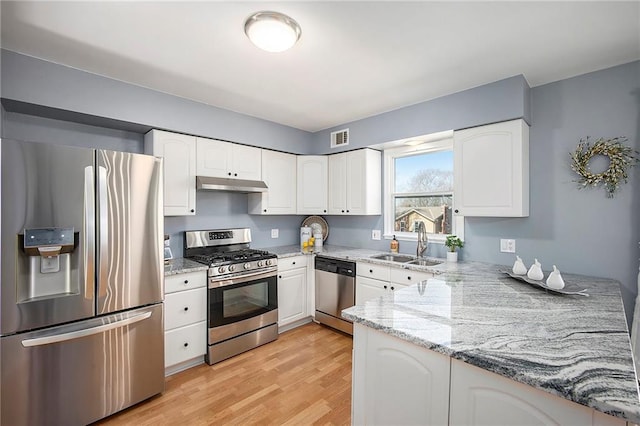 kitchen with light stone counters, visible vents, a sink, under cabinet range hood, and appliances with stainless steel finishes