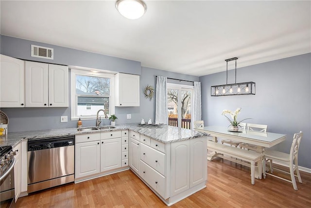 kitchen with visible vents, a sink, light stone counters, appliances with stainless steel finishes, and a peninsula