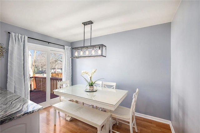 dining space with baseboards and light wood-style floors