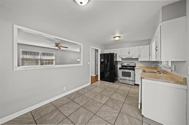 kitchen featuring light countertops, freestanding refrigerator, electric stove, white cabinetry, and a sink