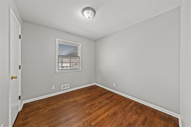 empty room featuring dark wood finished floors and baseboards