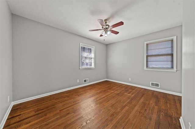 unfurnished room featuring wood finished floors, visible vents, and baseboards