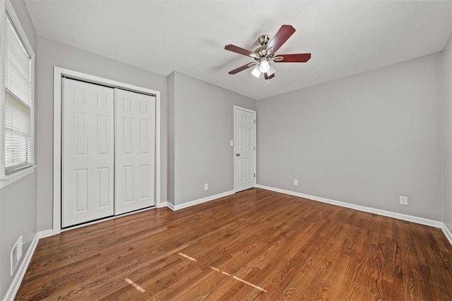 unfurnished bedroom featuring a ceiling fan, wood finished floors, baseboards, and a closet