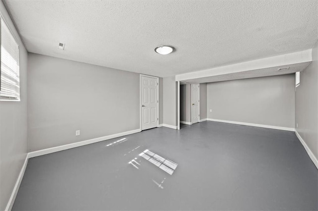 below grade area with visible vents, baseboards, and a textured ceiling