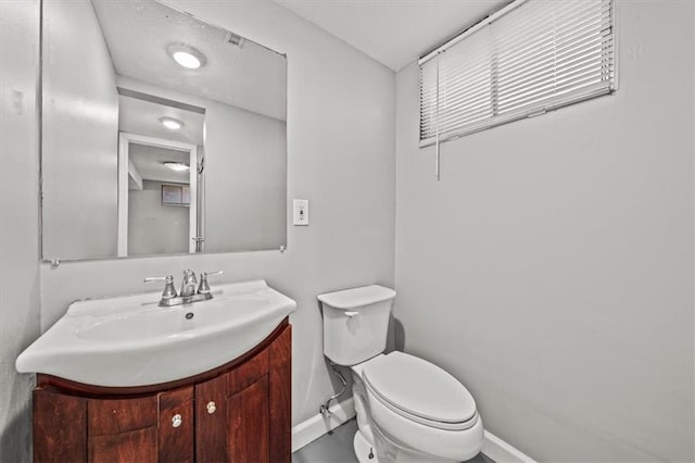 half bathroom featuring toilet, vanity, and baseboards