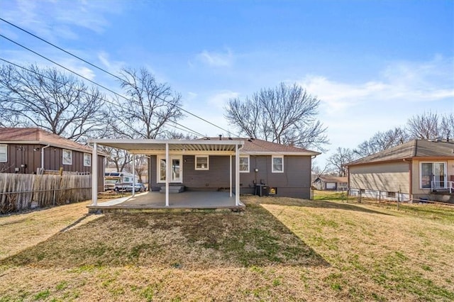 rear view of property featuring a patio, a lawn, and fence