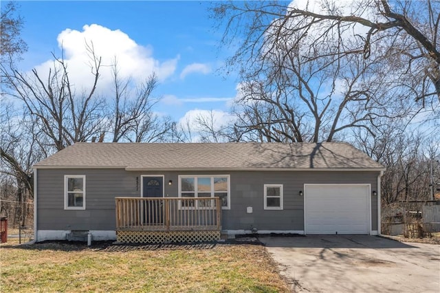 single story home featuring a shingled roof, a front lawn, a wooden deck, driveway, and an attached garage