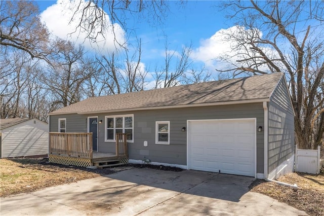 ranch-style house with a garage, roof with shingles, a deck, and driveway