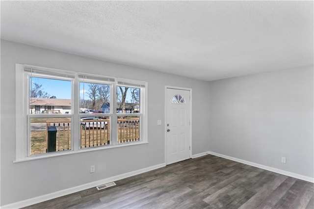 entryway featuring visible vents, a textured ceiling, baseboards, and wood finished floors