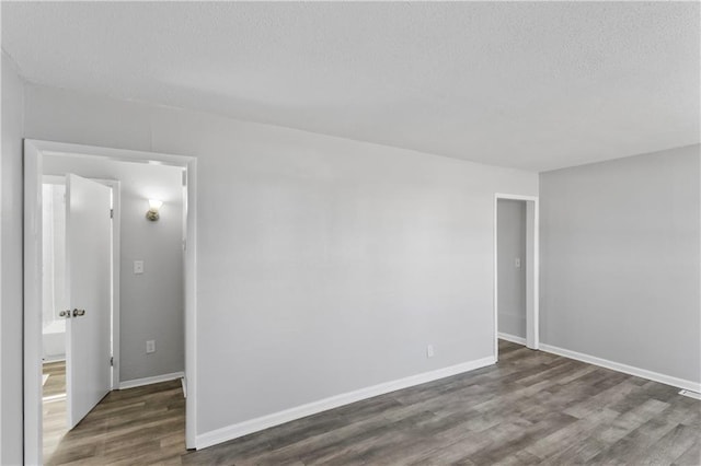 empty room featuring baseboards, a textured ceiling, and wood finished floors