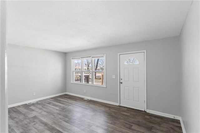 foyer entrance with visible vents, baseboards, and dark wood finished floors