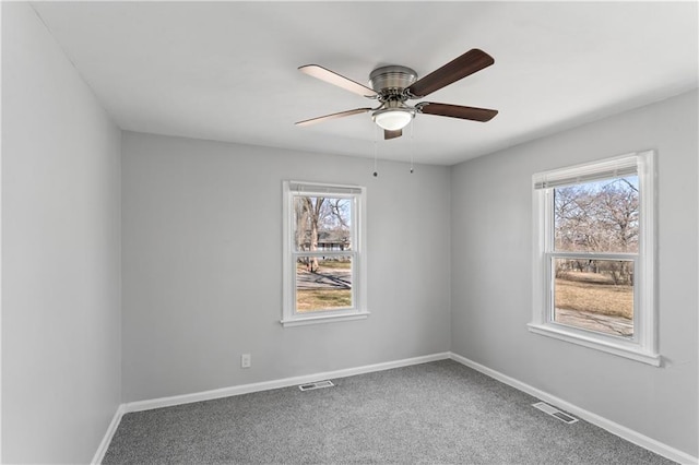 carpeted empty room with baseboards, visible vents, and ceiling fan