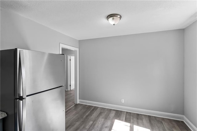 unfurnished dining area featuring wood finished floors, baseboards, and a textured ceiling