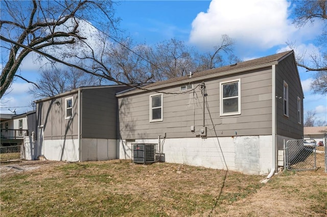 back of house featuring a gate, a yard, central AC, and fence