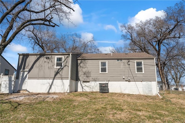 rear view of house featuring central air condition unit, a yard, and fence