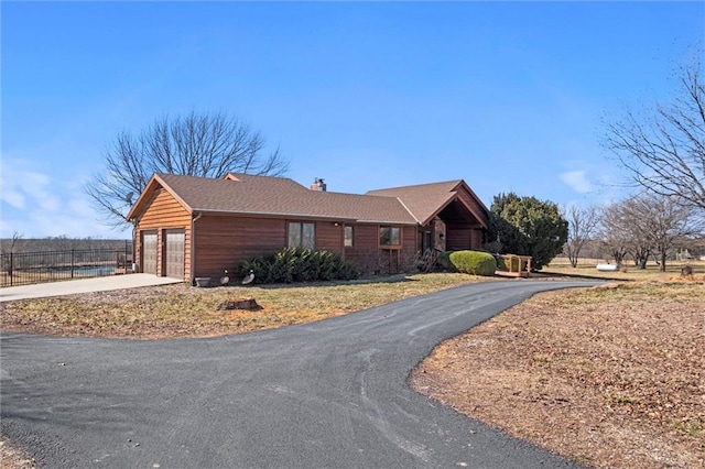 view of front of property with a chimney, a garage, and fence