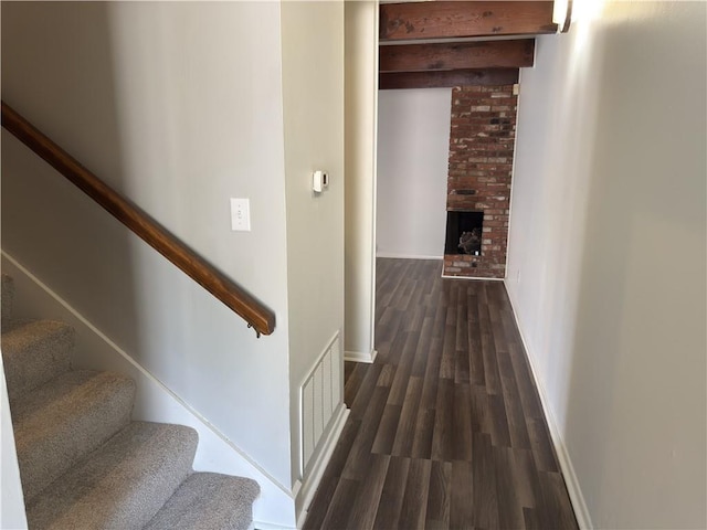 hallway featuring visible vents, stairs, dark wood-type flooring, and baseboards