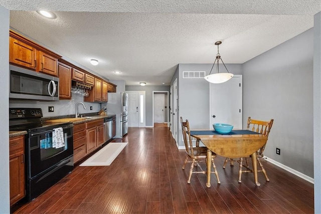 kitchen featuring appliances with stainless steel finishes, dark wood-style floors, and brown cabinetry