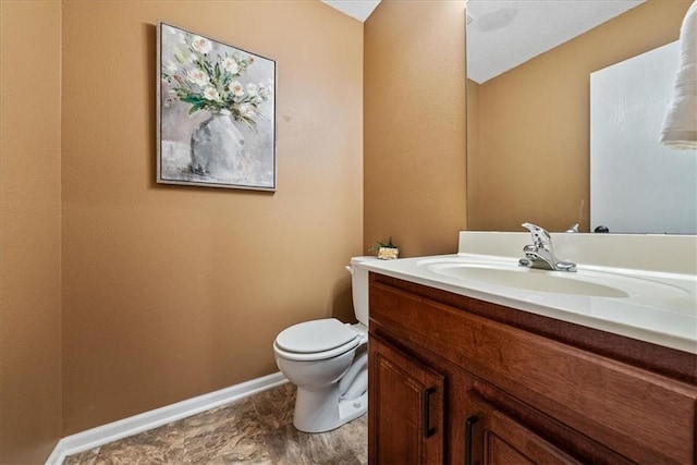 half bathroom with vanity, toilet, and baseboards