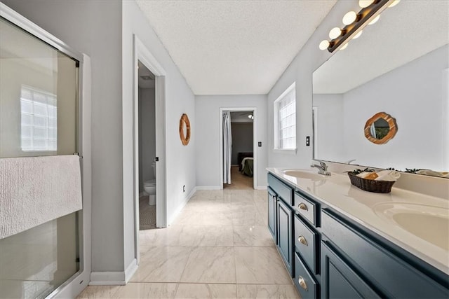 bathroom with double vanity, a sink, a textured ceiling, toilet, and marble finish floor