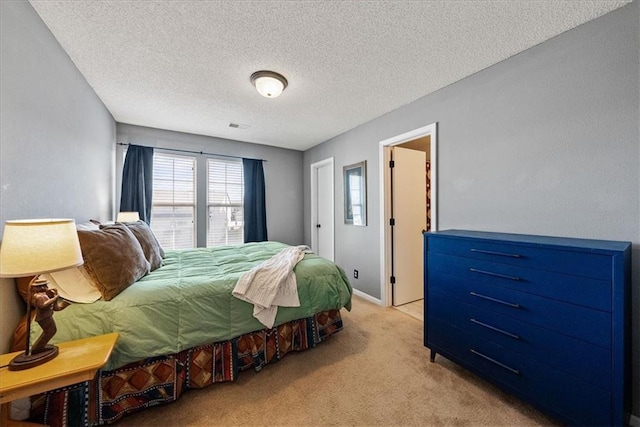 bedroom featuring light colored carpet, visible vents, and a textured ceiling